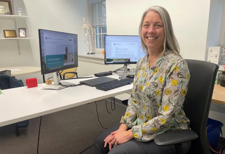 Woman sitting at desk smiling at camera 