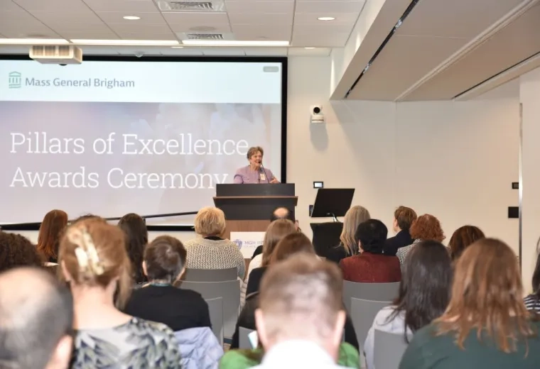 A woman stands at a podium with an audience in the foreground