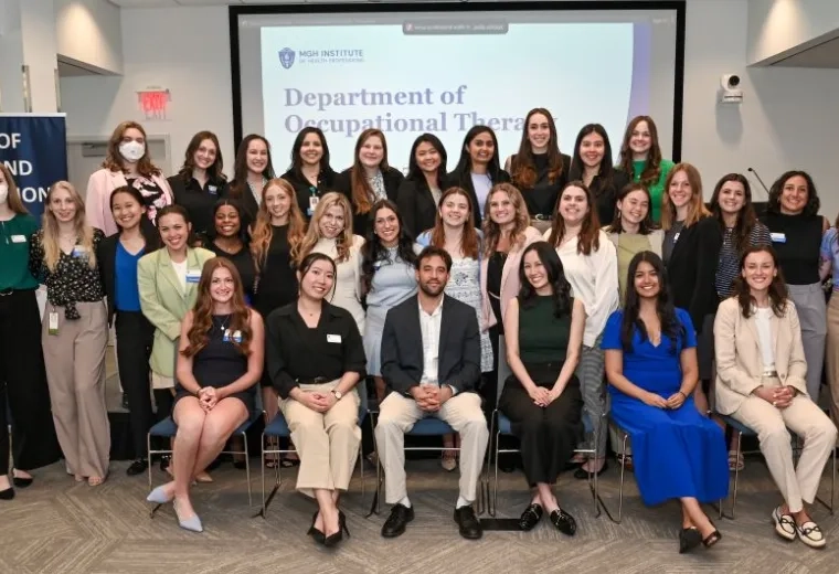 A group of people sit in rows in front of a screen that says Department of Occupational Therapy