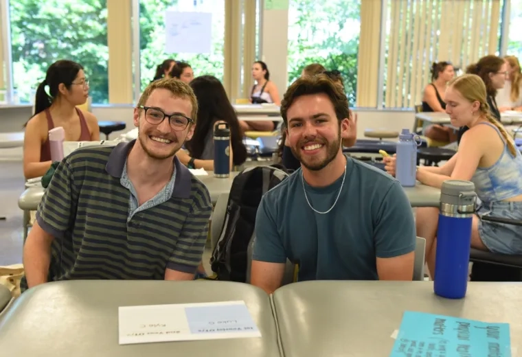 A photo of two men sitting in a classroom. 