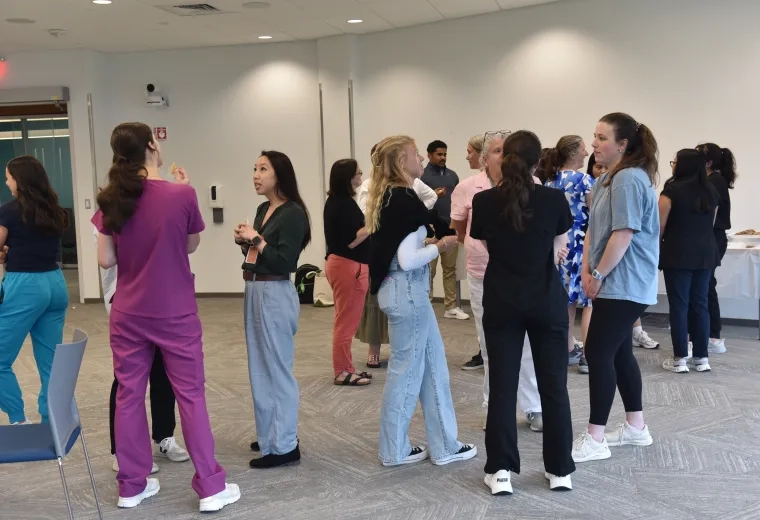 Small groups of people stand in a room conversing with each other