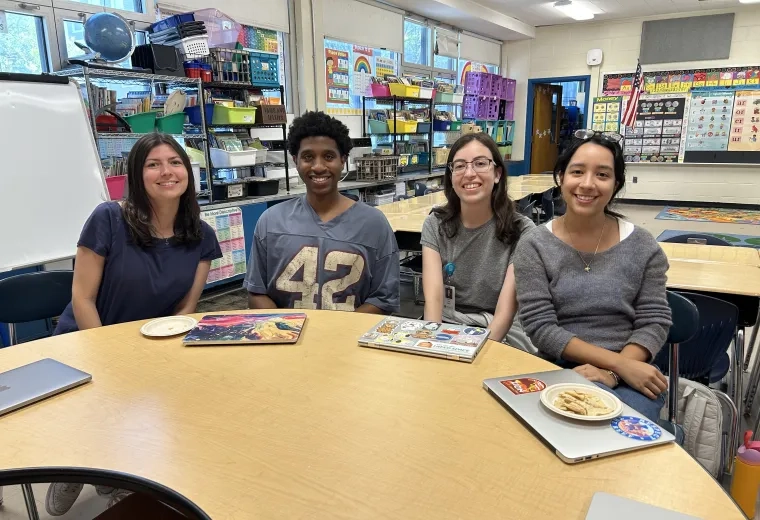 Four people sit at a classroom table
