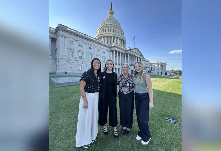 Four people pose with the US Capitol in the background