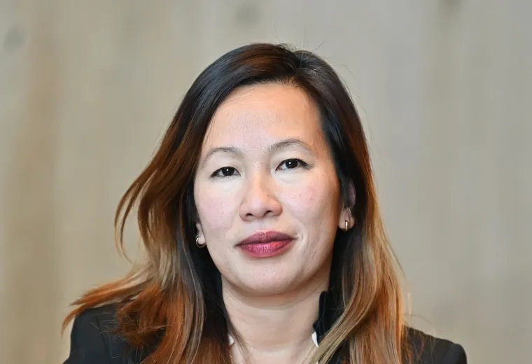 Headshot of woman with long brown hair looking at the camera and wearing a black jacket