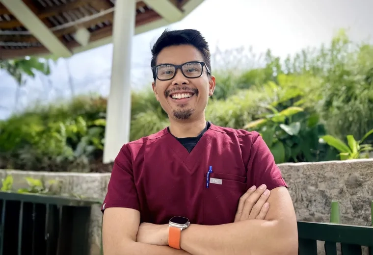 Man standing with big grin in a tropical location with arms folded