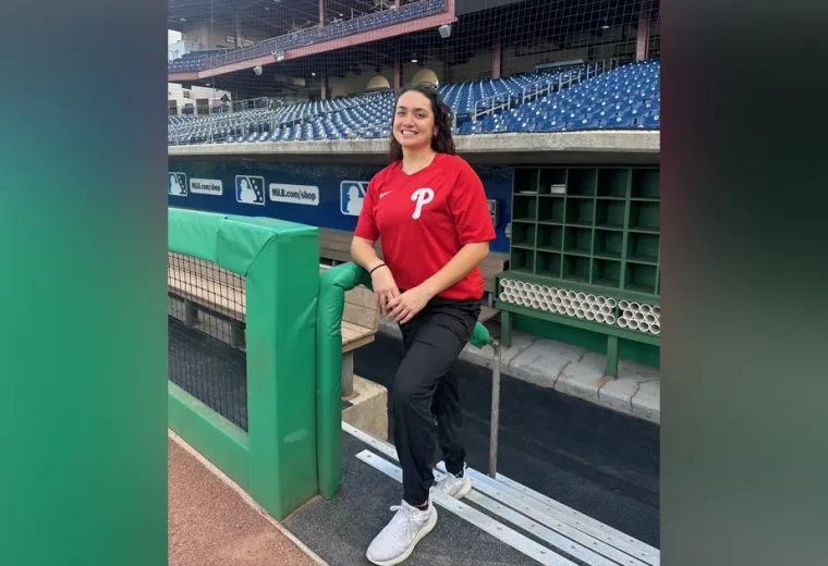 A woman stands on the stairs of a baseball field dugout