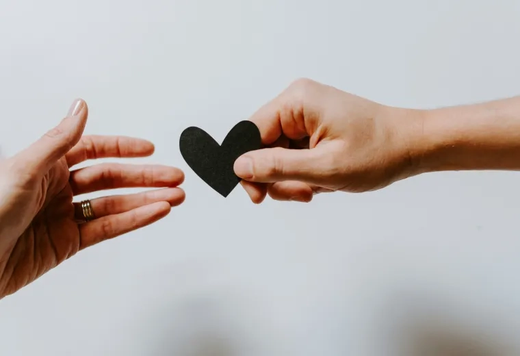 one hand handing a heart to another