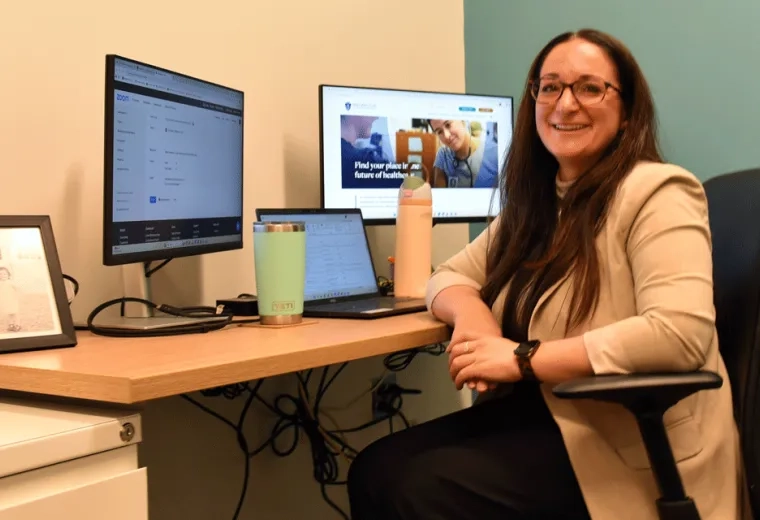 Lauren Finn sits at a desk in her office