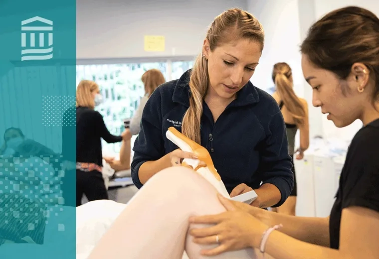 Two physical therapy students practicing hands-on techniques during a lab session, with a focus on joint manipulation.
