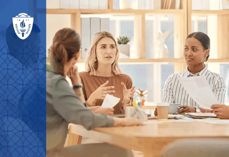 A workplace team gathers around a conference table while one person leads a discussion on inclusive practices and collaboration. 