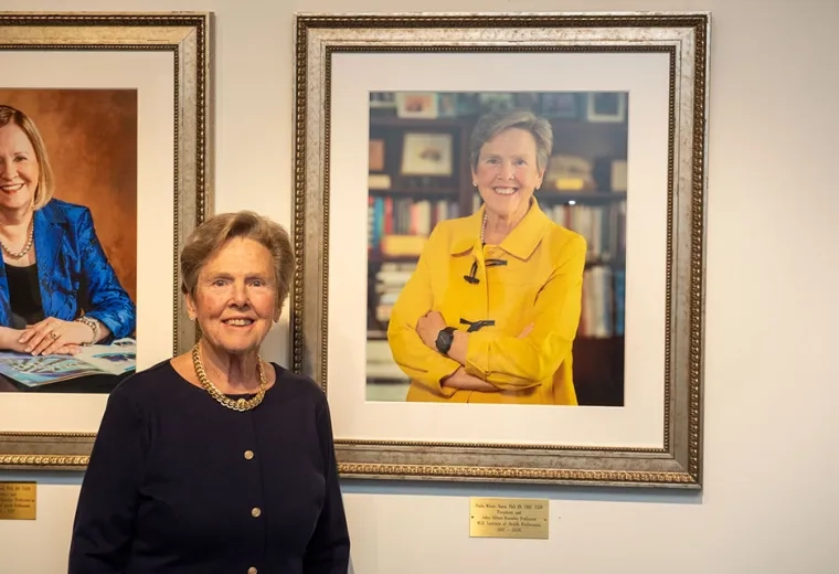 Paula Milone-Nuzzo stands in front of her portrait at the unveiling ceremony