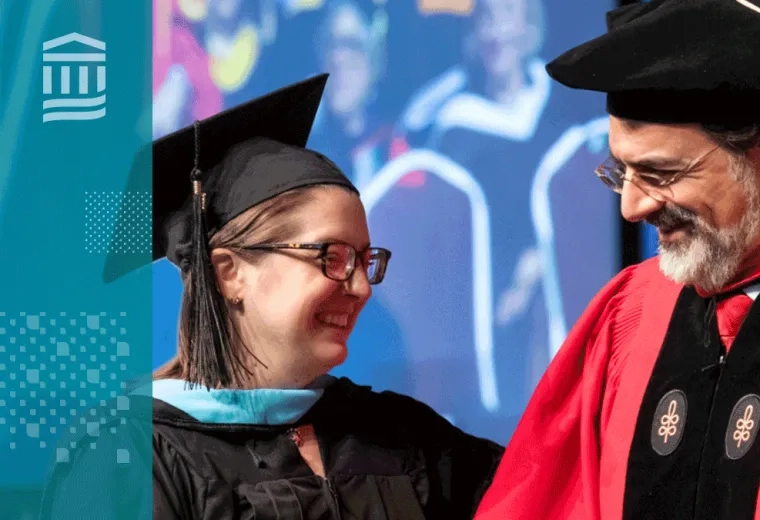 professor in graduaiton regalia (cap and red gown) smiles at a woman graduating who is in blue regalia