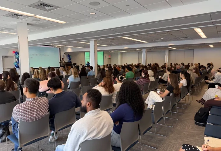photo of large room with rows of people sitting in chairs