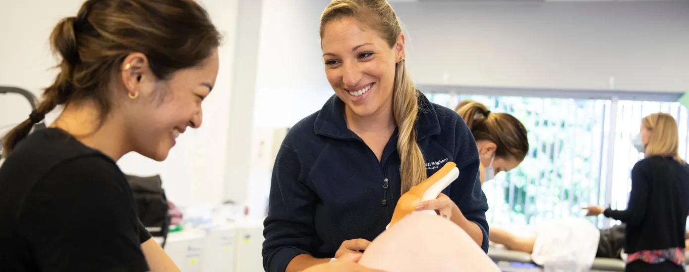 two students look at a person's knee and compare it to a plastic model of a knee