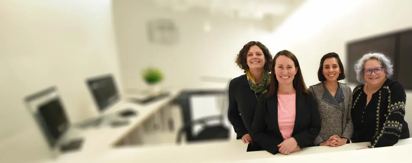 four women stand behind a desk