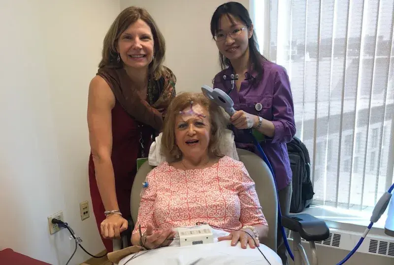 Two BRL Team Members Working together holding a device that looks like a T to a patient's head