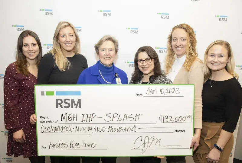 a group stands holding a check that says RSM, MGH IHP Splash $192,000