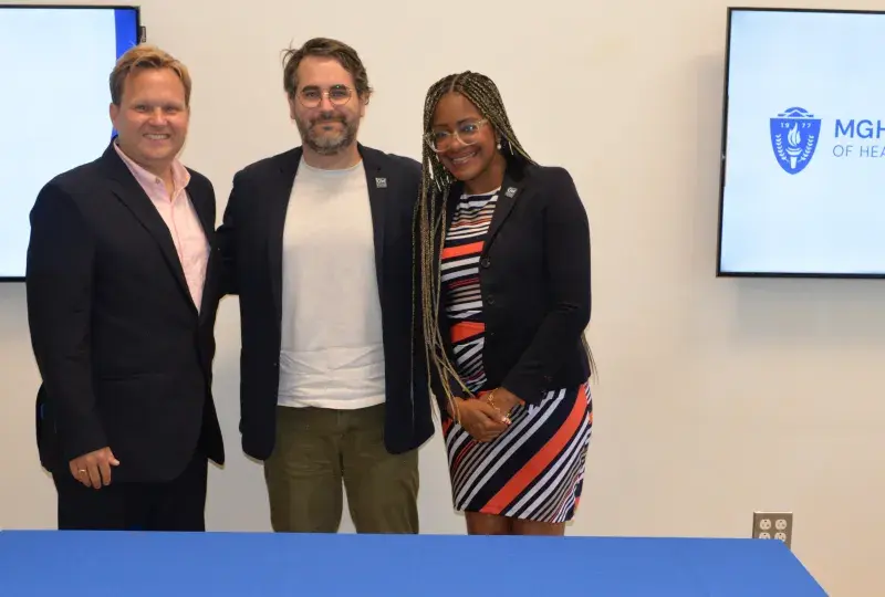 3 people standing in front of a table. 