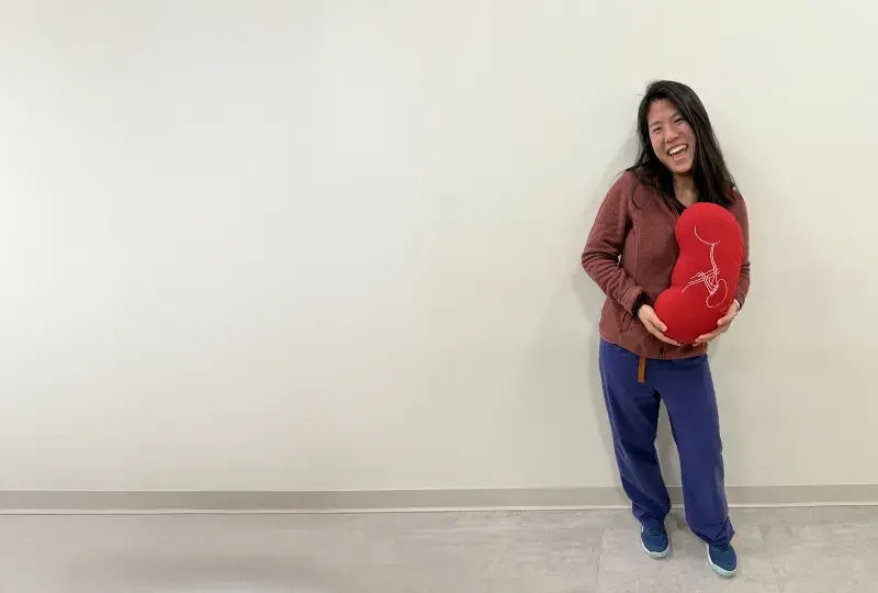 woman holds a kidney shaped pillow