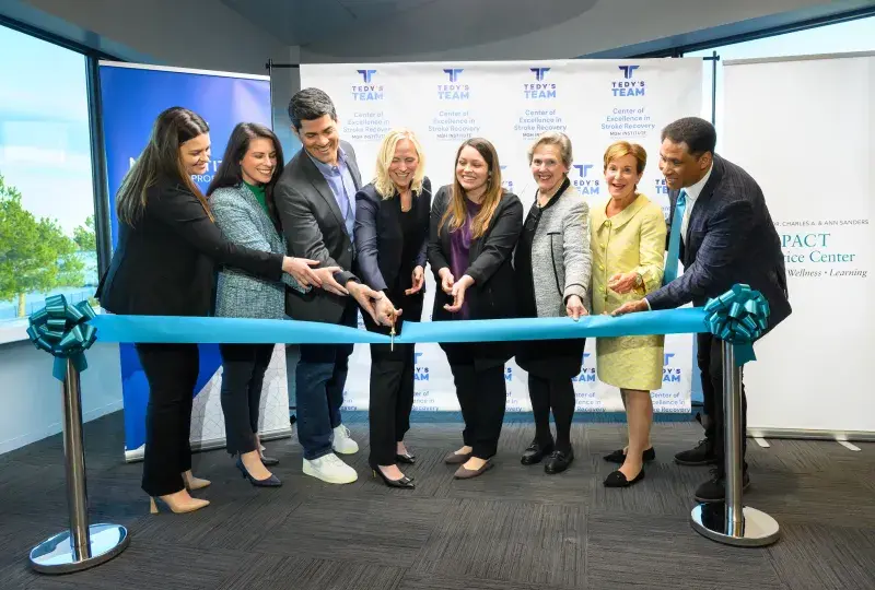 People cutting a ceremonial teal ribbon