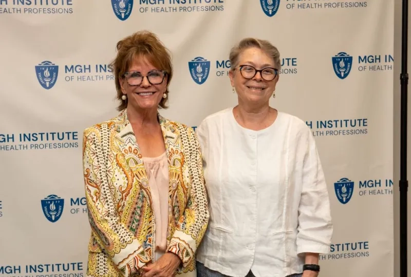 Two women standing in front of a backdrop