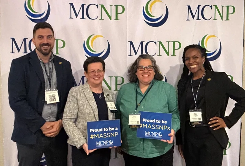 Four MGH Institute alumni pose for a photo in front of a banner for MCNP