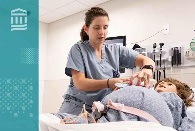 woman in scrubs adjusts a strap on a pregnant manikin in a hospital bed