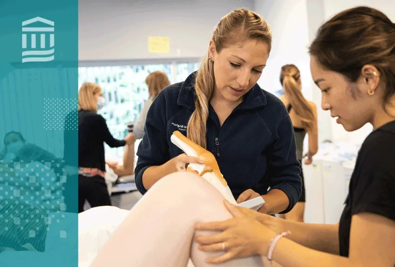 Two physical therapy students practicing hands-on techniques during a lab session, with a focus on joint manipulation.