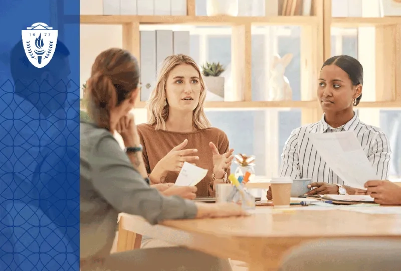 A workplace team gathers around a conference table while one person leads a discussion on inclusive practices and collaboration. 
