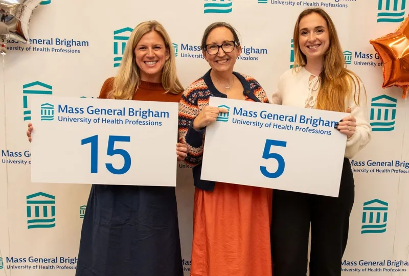 Three women hold up signs with numbers on them