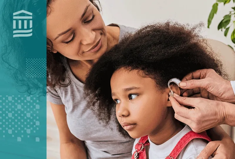 woman has arm around her daughter who is getting fitted for a hearing aid