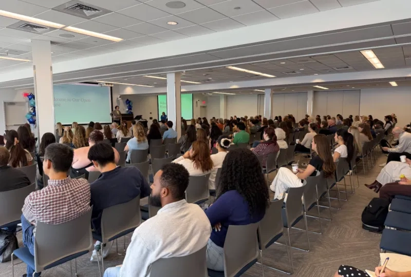 photo of large room with rows of people sitting in chairs