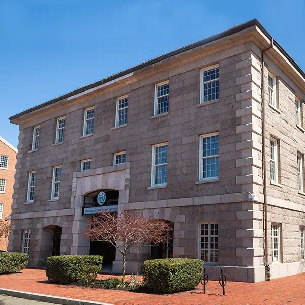 Shouse building is square and made of grey bricks against a blue sky