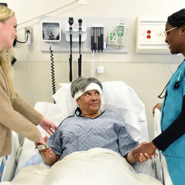 Fast-Track BSN Program students working with a standardized patient in a hospital setting during their clinical rotations. This second-degree nursing program provides hands-on training and intensive nursing education designed for a quick transition into nursing roles.
