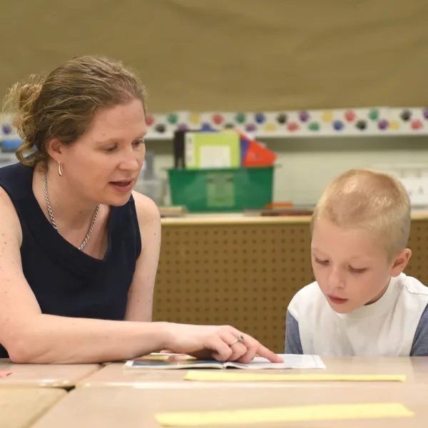 A literacy educator from the Literacy and Language Certificate Program working one-on-one with a student to improve reading skills. The program provides educators with advanced literacy strategies and evidence-based instruction techniques for literacy education.
