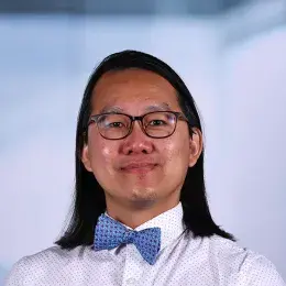 chris wears a blue bowtie and has long straight brown hair