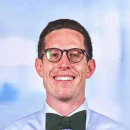 Alex Wolf wearing glasses and in light blue shirt and green bowtie