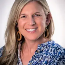 sarah has blonde hair and a blue patterned top