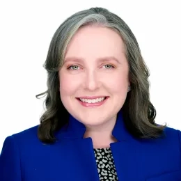 Headshot of Woman against a white background wearing a blue jacket 