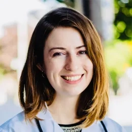 Headshot of Victoria Dubin with shoulder length dark blonde hair in front of a blurred outdoor background.