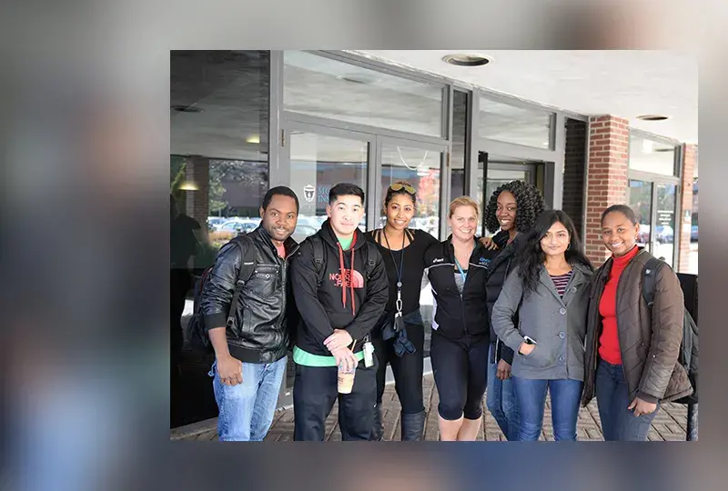 group of students stand in a line in front of a building