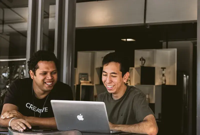 two men look at an apple laptop