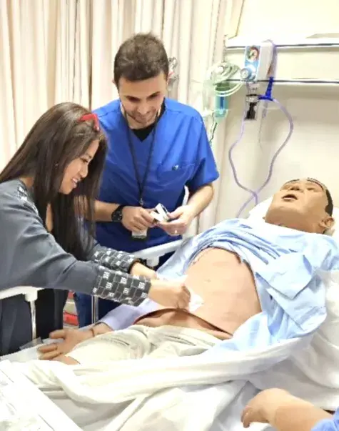 People working with a manikin in a hospital bed