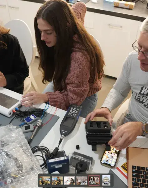 two women and man work with audiology equipment at table