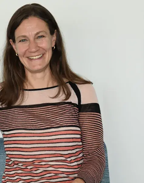 A woman sits on a couch facing the camera