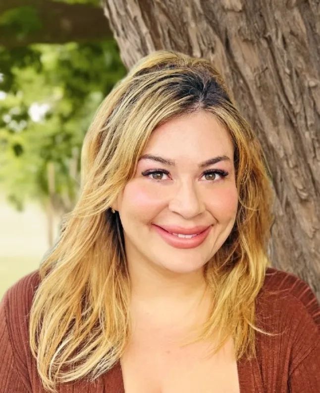 Rachel Terra Norton has medium length blonde hair and is wearing a brown shirt.