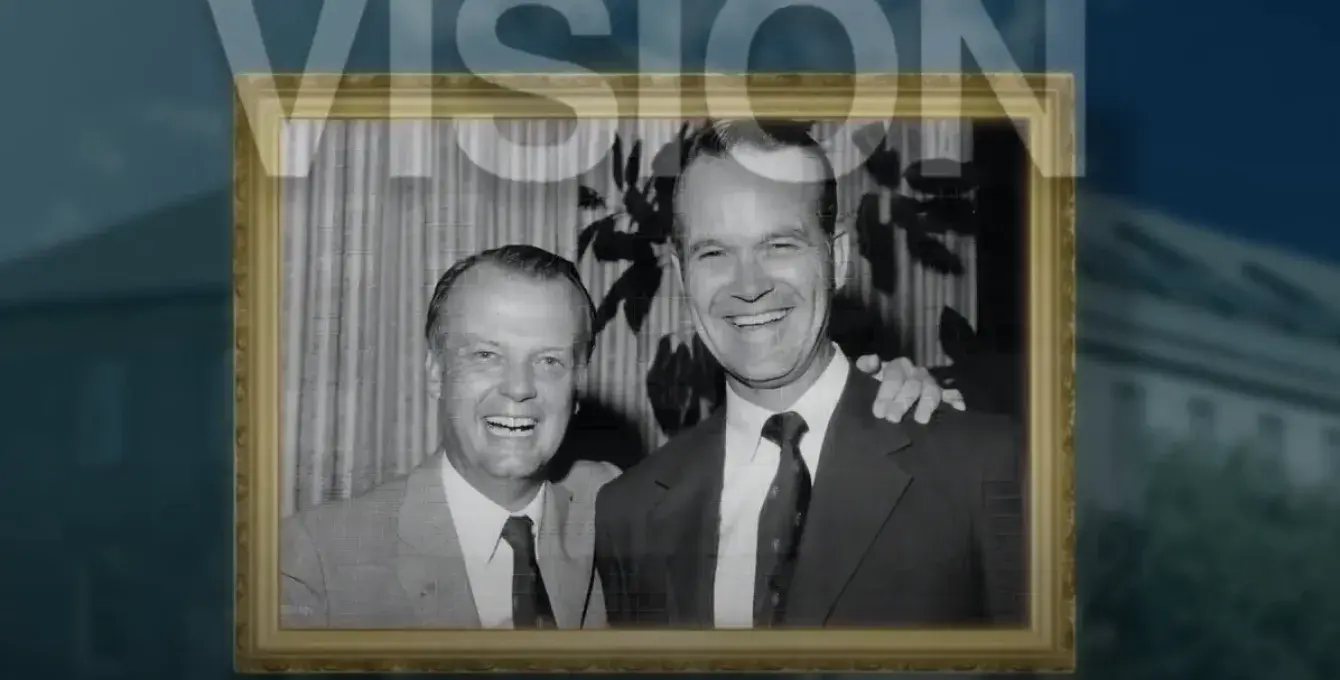 a black and white photo under the word VISION shows a man with his arm around the shoulders of another man